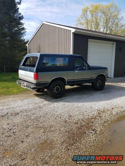 Dark blue and silver two-tone 1987 Ford Bronco parked in gravel driveway