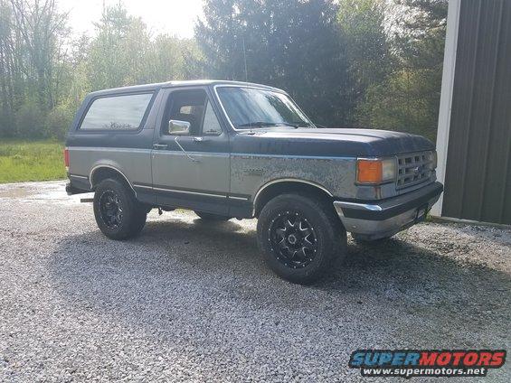 1987 Ford Bronco parked on gravel in front of a building
