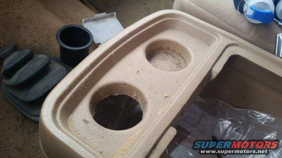 Center console with two cup holders, a gear shift boot, and a black cup holder insert
