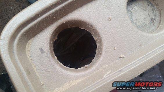 Close-up of a tan plastic cup holder with a hole in the center. Some debris is visible around the edges