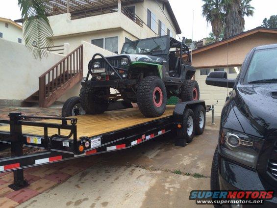 Modified Jeep Wrangler on a trailer, with a black pickup truck next to it