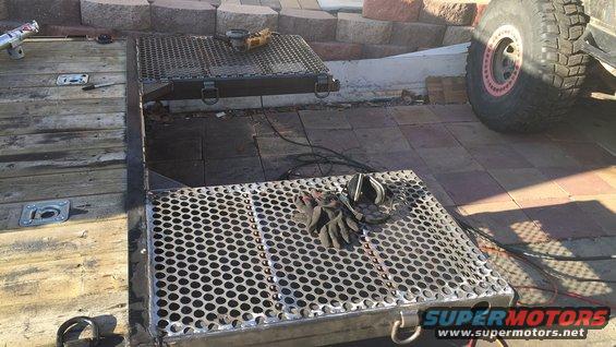 Trailer ramp with grinder, gloves, and a large off-road tire visible