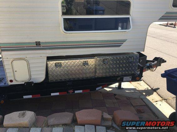 Truck camper side view with diamond plate toolboxes and striped decal