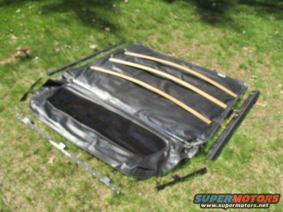 Vehicle soft top laid out on grass with wooden support bars