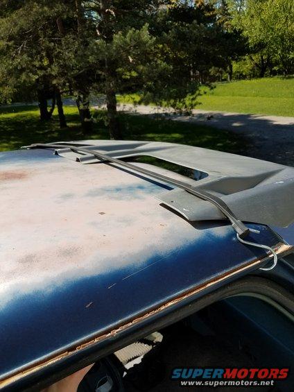 Close-up of a car's roof showing a sunroof opening and weathered paint