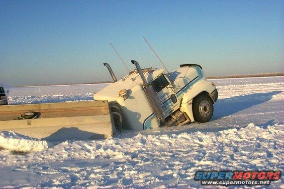 Semi-truck stuck in snowdrift, partially on a flatbed trailer