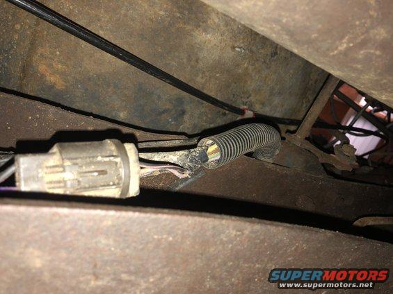 Close-up of a damaged electrical connector and wiring harness on a vehicle chassis