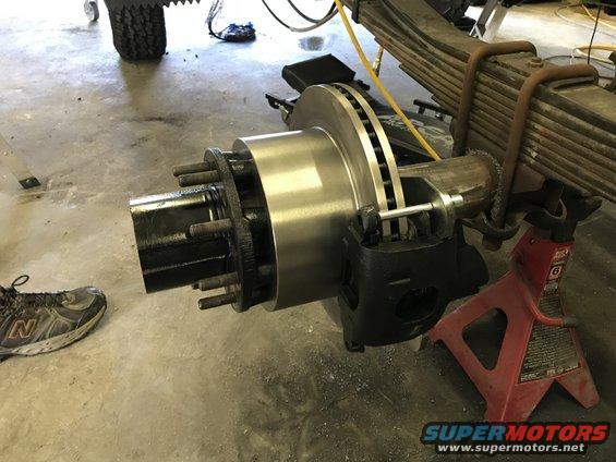 truck rear axle with brake rotor and caliper on jack stands