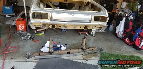 car body being worked on, bumper removed, jack and tools nearby