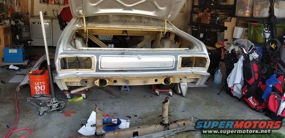 1974 Plymouth Duster rear end, stripped for restoration, with trunk open, jack and tools nearby