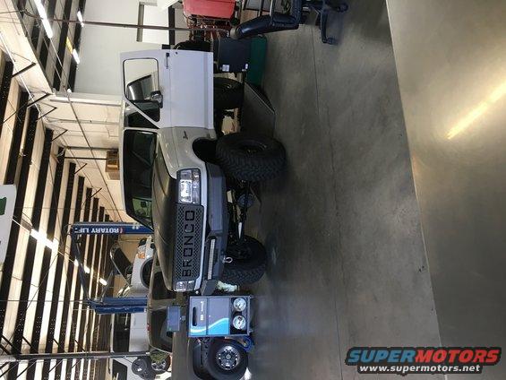 White Ford Bronco with black grille and "BRONCO" lettering, parked indoors