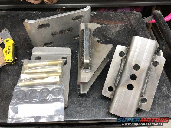 Metal brackets and a bag of bolts and washers on a workbench