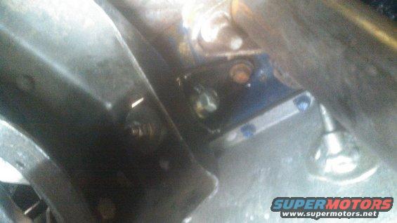 Close-up of engine bay with bolts and metal brackets, some painted blue