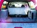 1994 Ford C-150 (Centurion Conversions) - Rear interior view of a red SUV with custom storage compartments and a folded rear seat.
