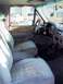 1994 Ford C-150 (Centurion Conversions) - Interior view of a truck, showing the seats and dashboard. A vintage white car is visible outside through the window.