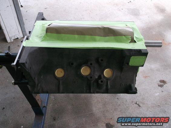 Engine block covered in masking tape and paper, mounted on a stand