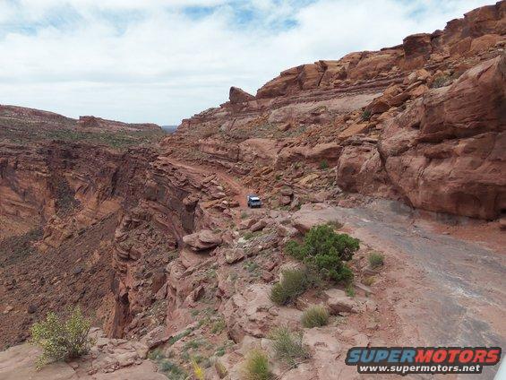 SUV driving on a narrow dirt road next to a steep canyon drop-off