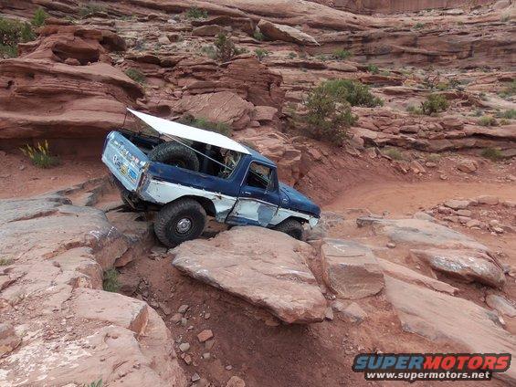 Blue and white 1978 Ford Bronco off-roading on a rocky desert trail