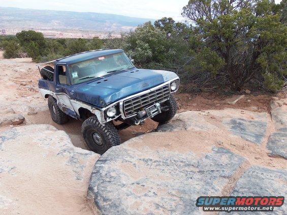 Blue and white 1978 Ford Bronco with winch, navigating rocky terrain