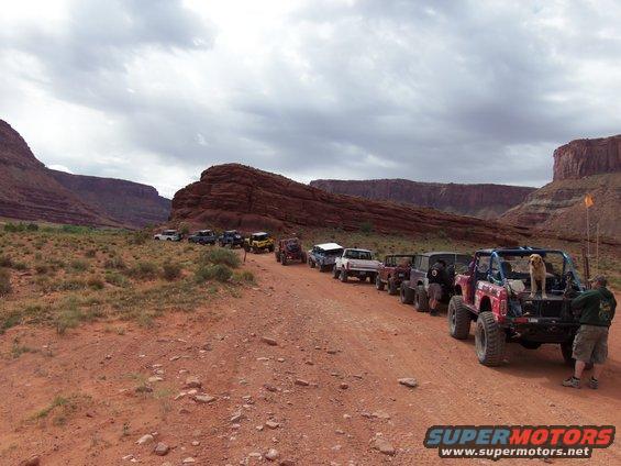 Line of off-road vehicles on a dirt road in a canyon landscape