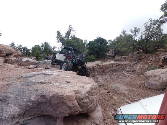 Off-road buggy navigating rocky terrain, with another vehicle partially visible