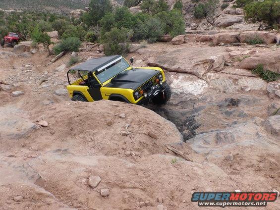 Yellow and black 1984 Ford Bronco navigating rocky terrain