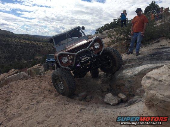 Brown off-road vehicle climbing rocks with winch and custom bumper
