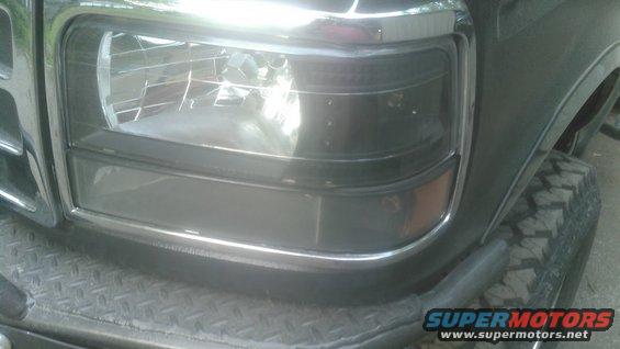 1992 Ford Bronco front headlight assembly with chrome trim and part of the grille