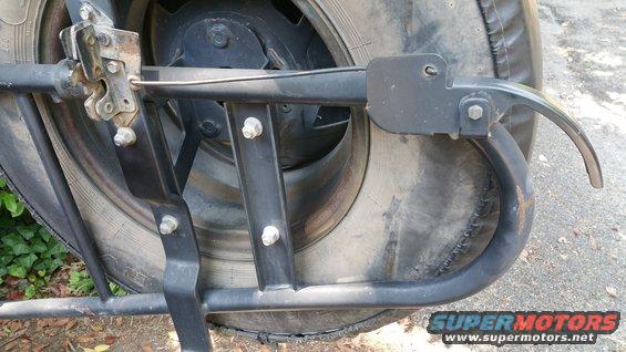 Close-up of a black metal spare tire carrier mechanism attached to a tire