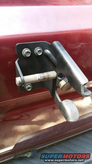 close-up of a black metal bracket with bolts and a pin attached to a red vehicle body