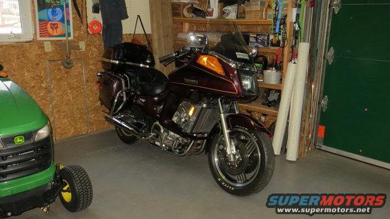 1983 Yamaha Venture motorcycle parked in a garage next to a green riding mower