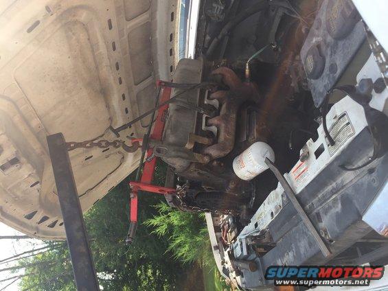 Engine hoist lifting an engine out of a vehicle's engine bay, with an oil filter visible