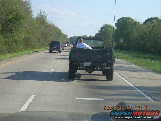 Dark pickup truck rear view on highway. License plate reads 1965
