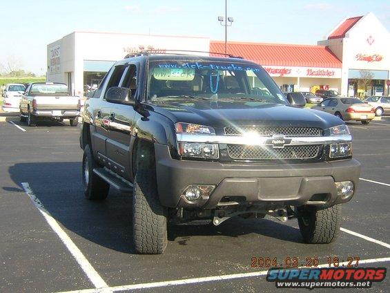 Front view of black Chevrolet Avalanche parked in a lot. "www.sick-trucks.com" sticker on windshield