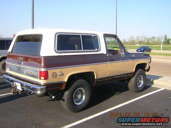 Brown and tan Chevrolet K5 Blazer with a white camper shell, parked in a lot