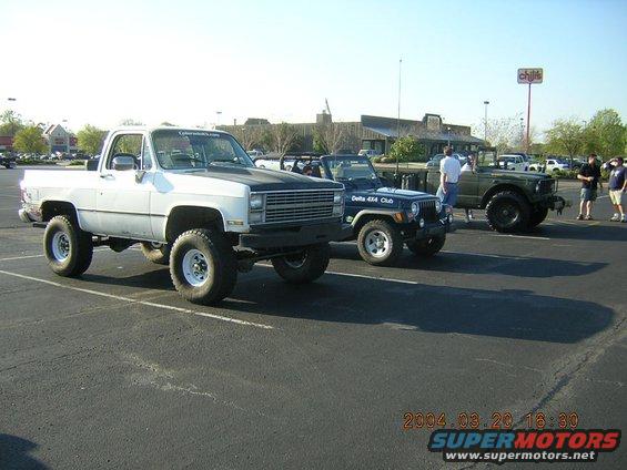 White 1984 Chevrolet K10 pickup truck, lifted with large tires, parked in a lot