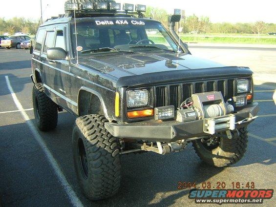 Modified Jeep Cherokee XJ with winch, light bar, and snorkel. "Delta 4x4 Club" sticker on windshield