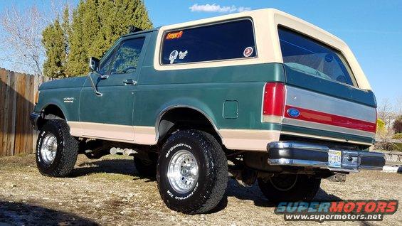 Green and tan Ford Bronco with aftermarket wheels and tires, viewed from the rear three-quarter angle