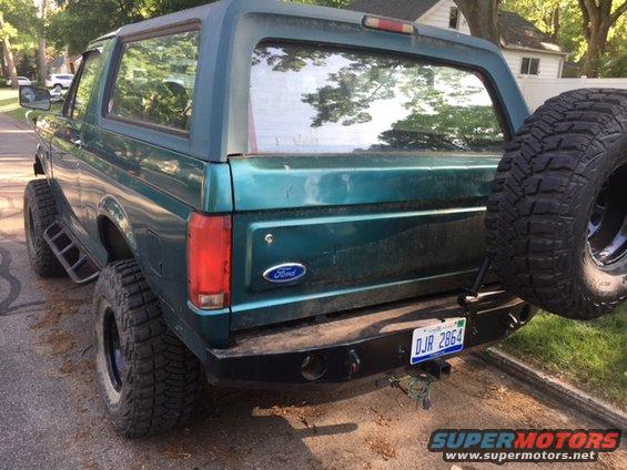 1996 Ford Bronco rear view showing spare tire mounted on swing away carrier, aftermarket bumper, and license plate DJR 2864