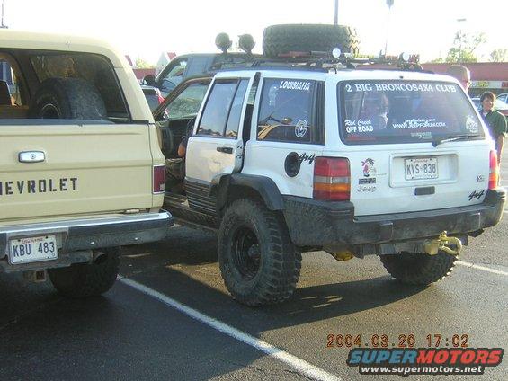 White Jeep Grand Cherokee rear view, lifted with off-road tires and roof rack