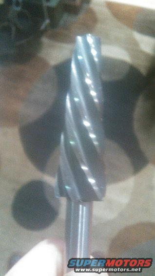 Close-up of a rotary file bit with spiral flutes. Supermotors.net logo at bottom