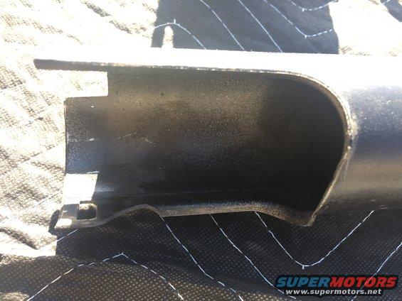 Black metal engine part with a curved opening, resting on a quilted black surface