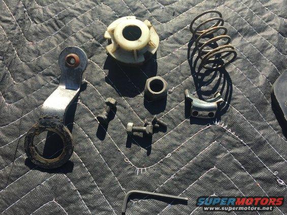 Assorted metal and plastic steering column components and fasteners on a quilted mat
