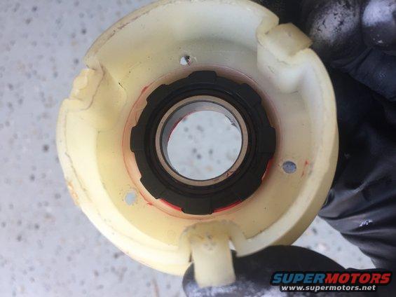 Close-up of a yellow plastic steering column bearing housing with a black seal and bearing inside