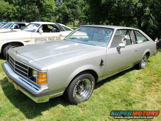 Silver coupe with chrome grille, square headlights, and an eagle decal on the fender