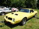 1971 Ford Ranchero - A yellow Pontiac Firebird Formula is displayed outdoors next to another car, with people gathered around.