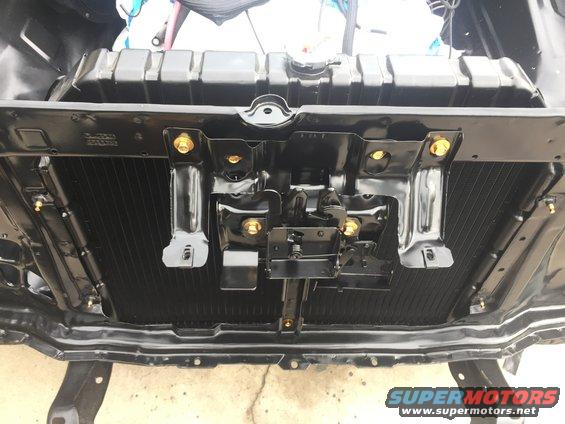 Black radiator and black metal brackets with gold bolts, viewed from front