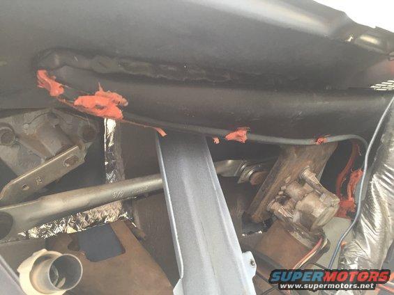 Under-dash view of HVAC components, wiring, and insulation. Orange sealant is visible
