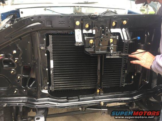 radiator and condenser assembly with latch mechanism, person's hand adjusting a cable