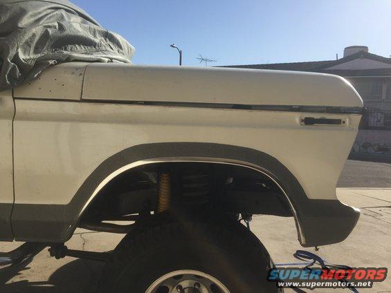 White SUV fender and tire, partially covered by a tarp